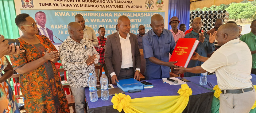 Kaimu Mkurugenzi wa Halmashauri ya Wilaya ya Ushetu Bw. Deus Kakulima Antony akikabidhi Daftari la kuhifadhia kumbukumbu za Hati Miliki za Kimila kwa Afisa Ardhi Mteule wakati wa Zezi la ugawaji Hati katika Kijiji cha Igunda 25/09/25